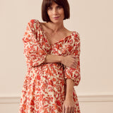 Albaray cream midi dress with orange botanical print, made from 100% organic cotton. Features a gathered tie neckline, ¾ sleeves, elasticated waist, and lined skirt with pockets – ideal for everyday comfort and effortless style.