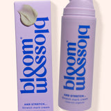 Bloss & Soak Stretch Mark Cream in a lavender pump bottle next to its matching lavender box packaging, set against a solid cream background.