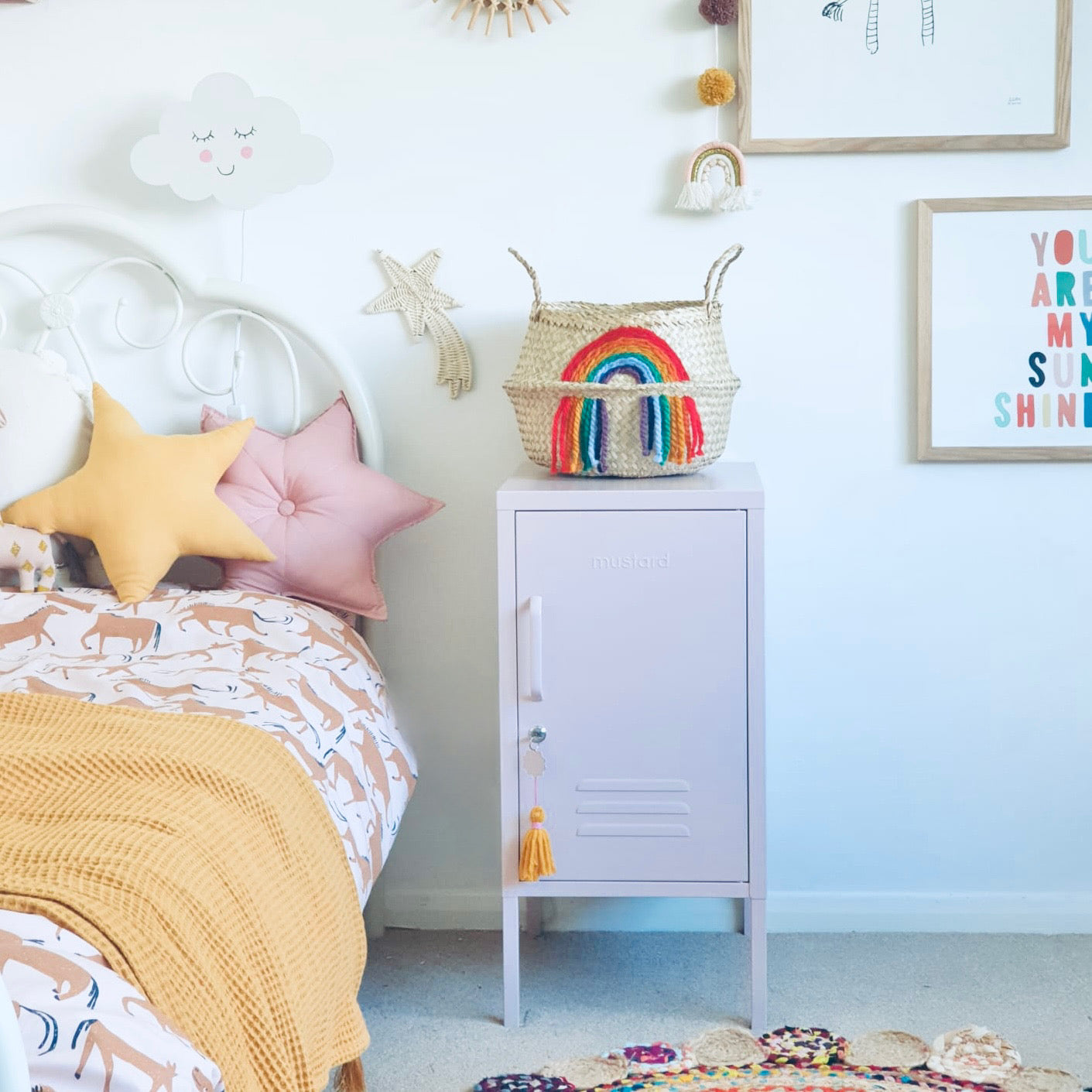 Vivid Rainbow Belly Basket on top of a pale pink locker beside a child's bed with star cushions
