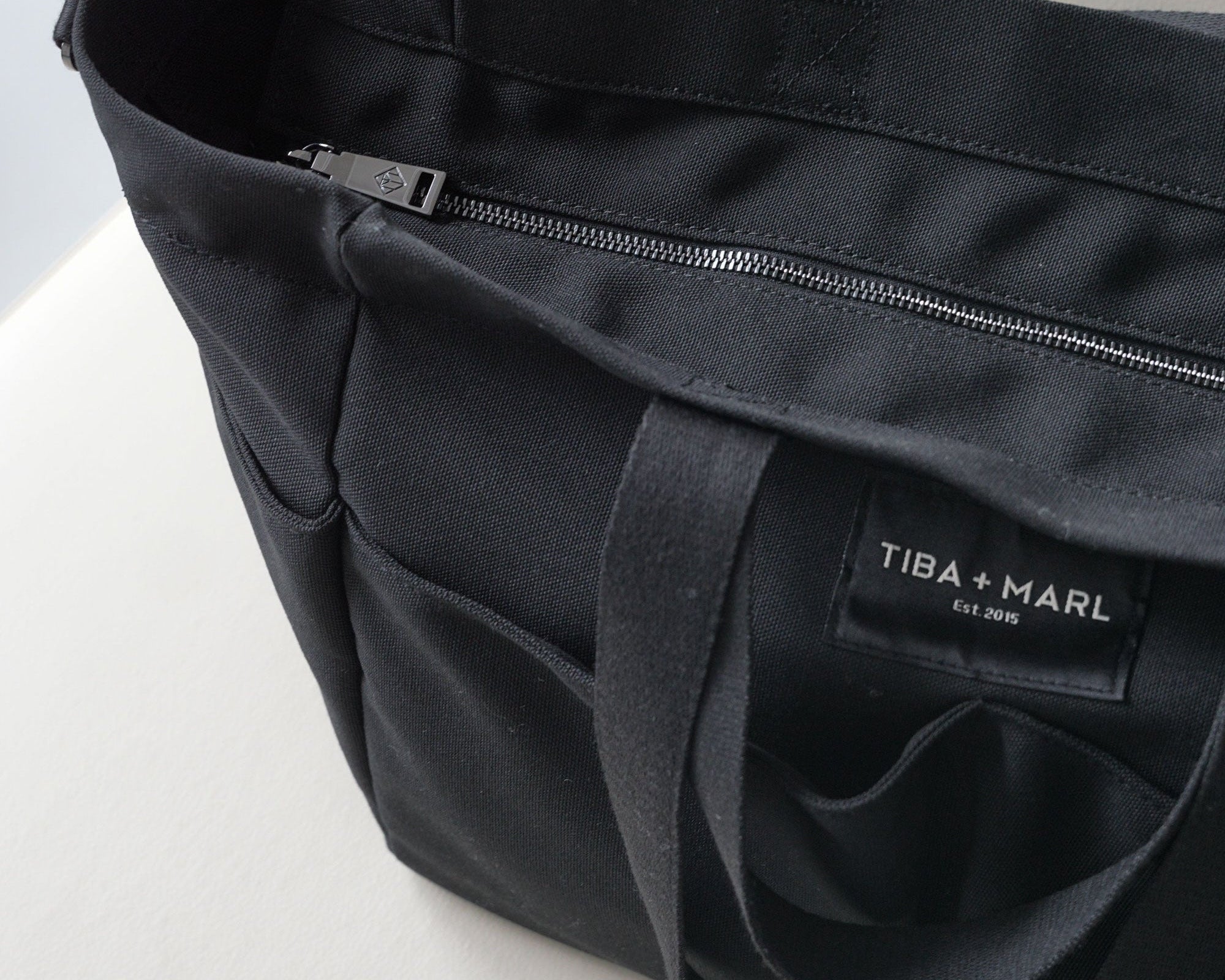Black tote bag with 'Tiba + Marl' label on a white background