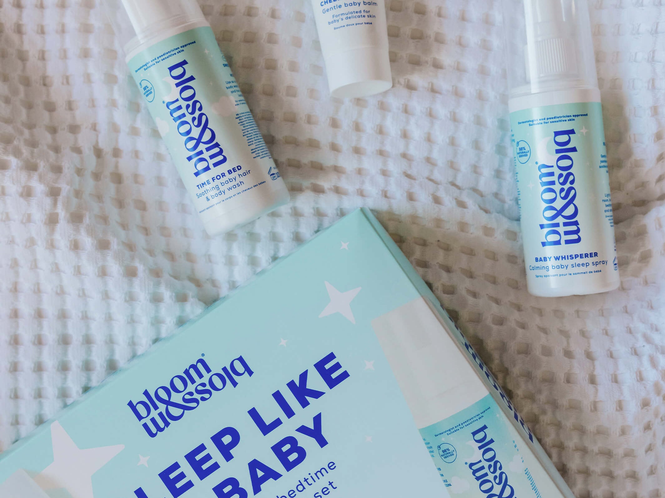 Blossom Sleep Like a Baby routine gift set including a box, spray bottle, tube, and pump bottle, arranged on a white textured blanket.