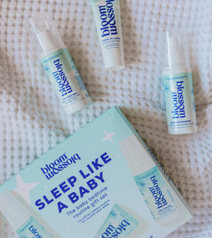 Blossom Sleep Like a Baby routine gift set including a box, spray bottle, tube, and pump bottle, arranged on a white textured blanket.