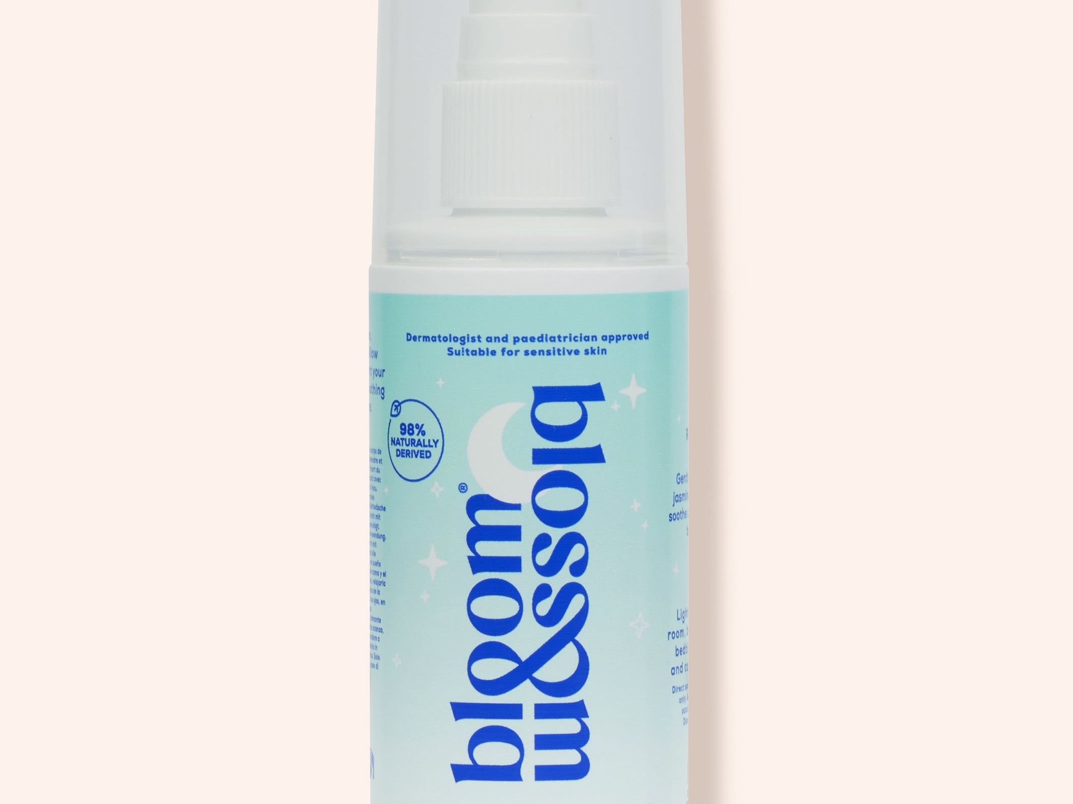A bottle of Blossom & Soho Baby Whisperer calming baby sleep spray, featuring a white and light blue design with a white spray cap, set against a solid pale peach background.