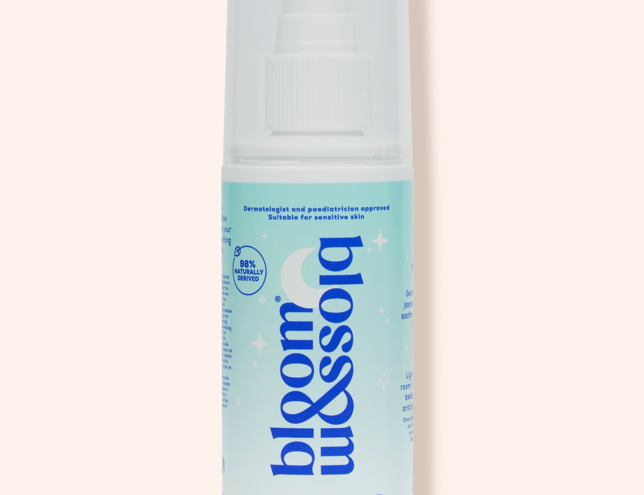 A bottle of Blossom & Soho Baby Whisperer calming baby sleep spray, featuring a white and light blue design with a white spray cap, set against a solid pale peach background.