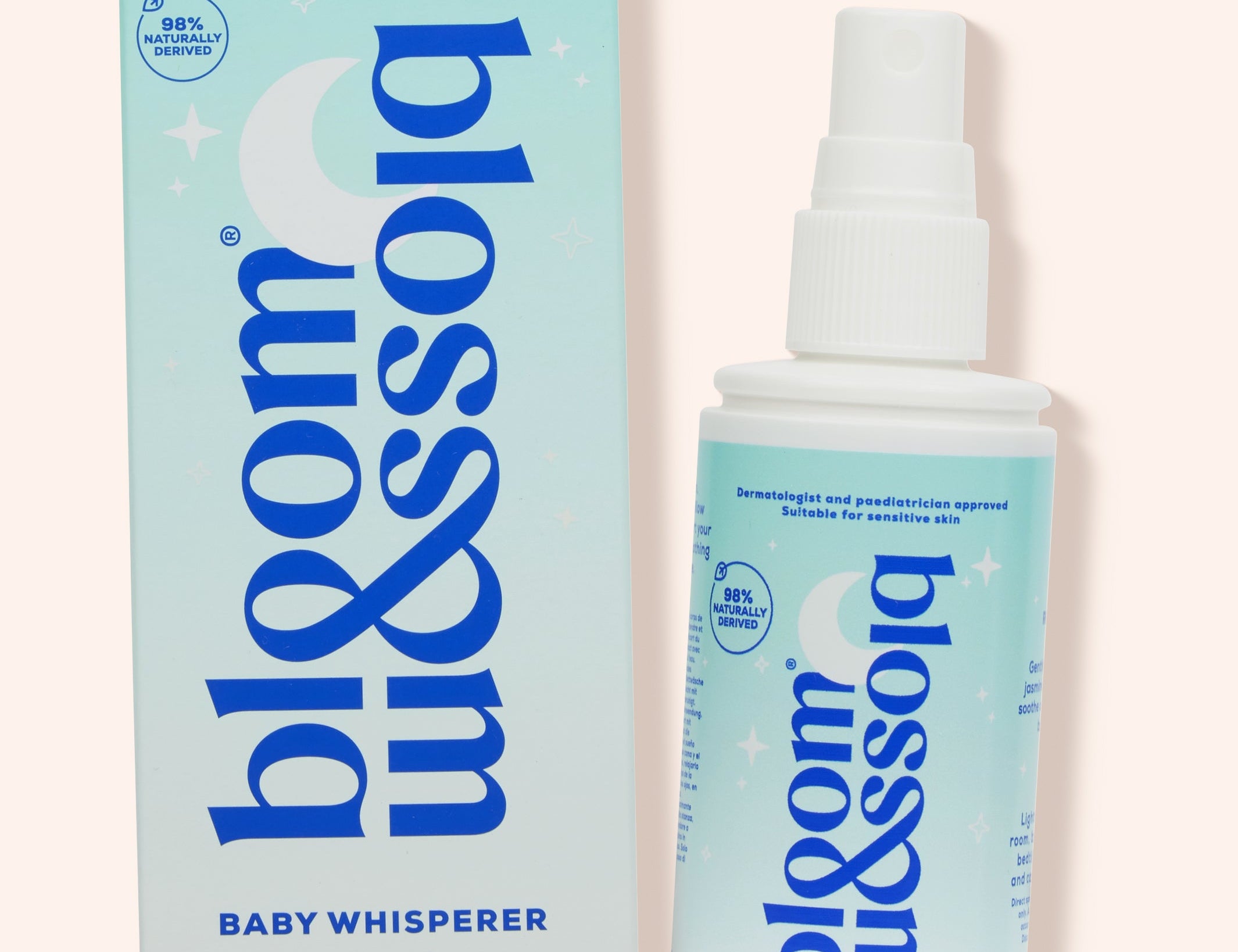 Blossom & Soho Baby Whisperer calming baby sleep spray shown with its light blue and white packaging box and spray bottle on a pale pink background.