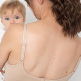 Woman wearing a beige compression garment with a baby peeking from behind.