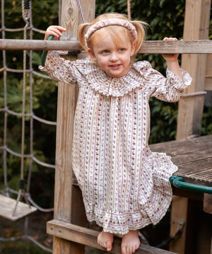 Beatrice Rose Stripe nightie, child standing on a wooden play frame in the frilled-collar floral striped nightie