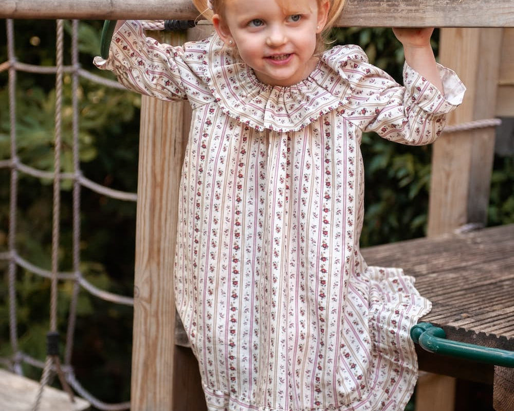 Beatrice Rose Stripe nightie, child standing on a wooden play frame in the frilled-collar floral striped nightie