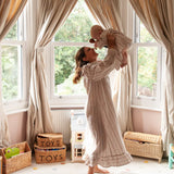 Beatrice Rose Stripe nightie worn by a woman lifting a smiling baby overhead in a bright bay-windowed nursery