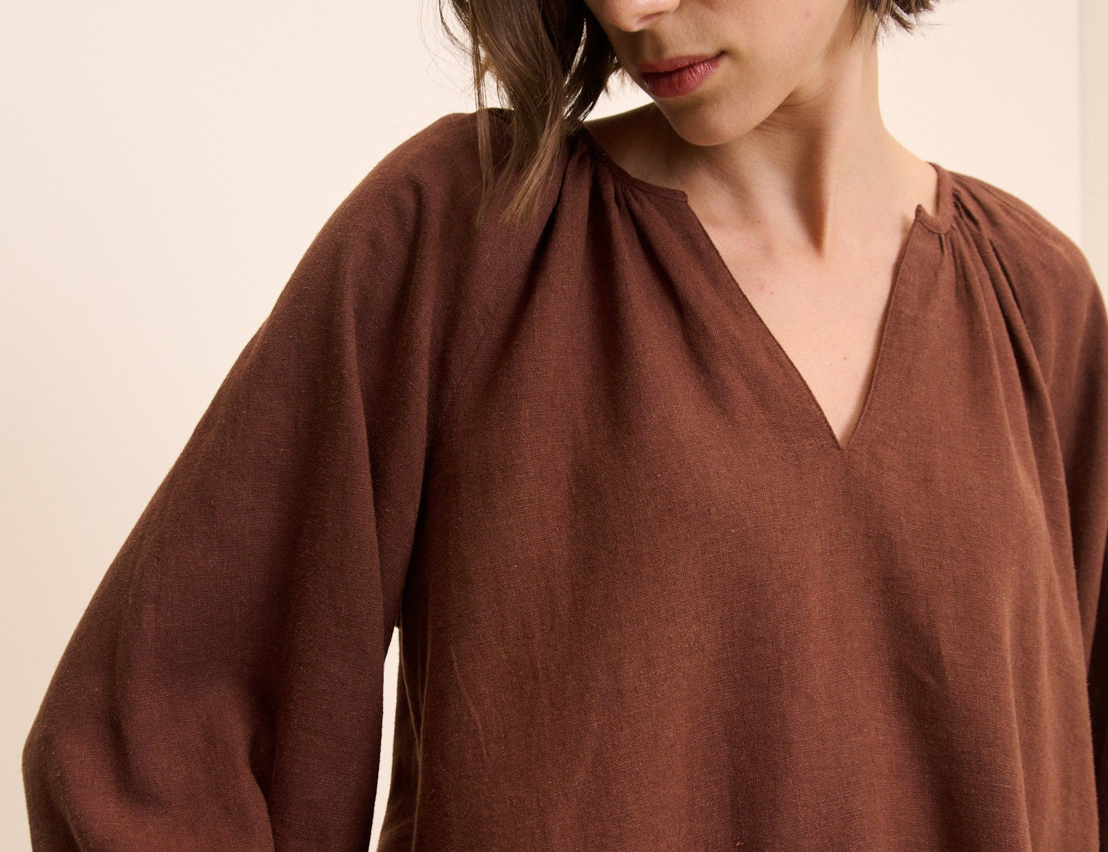 Woman wearing a brown blouse against a beige background