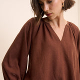 Woman wearing a brown blouse against a beige background
