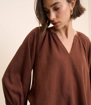 Woman wearing a brown blouse against a beige background