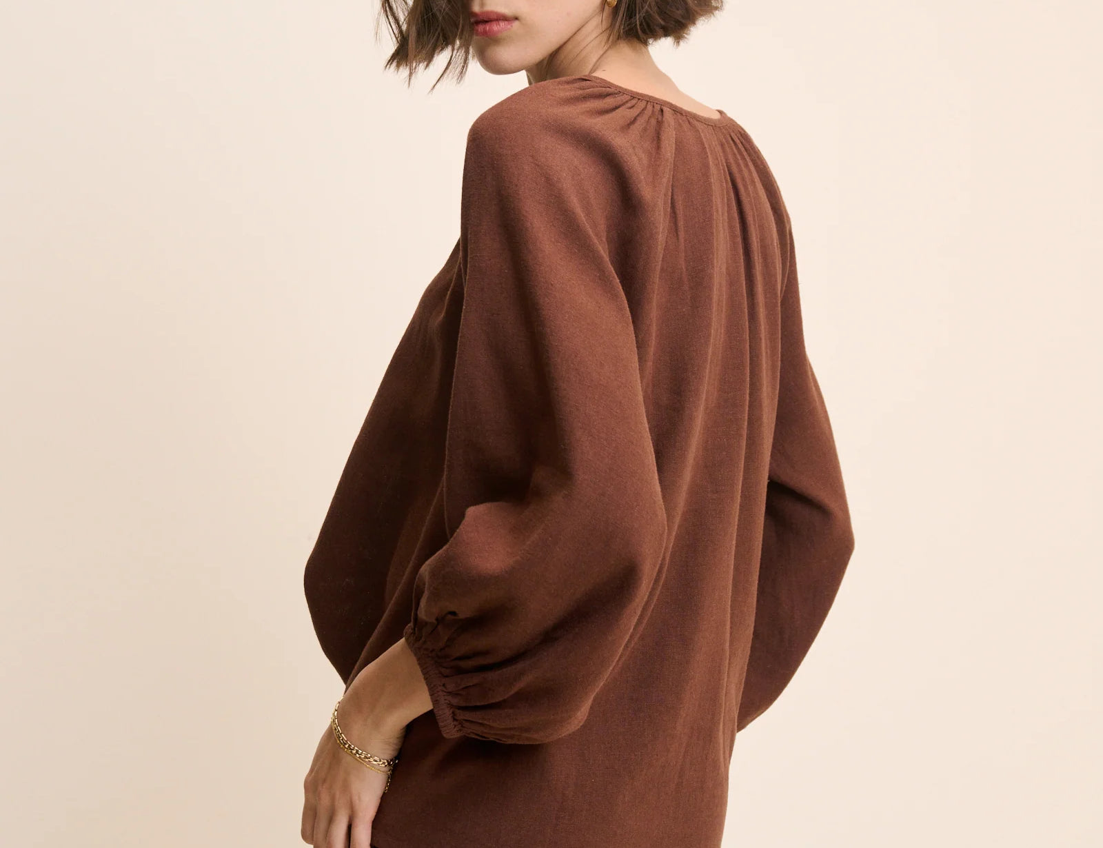 Woman wearing a brown outfit against a beige background