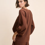 Woman wearing a brown outfit against a beige background