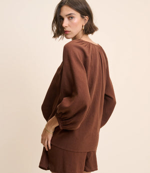 Woman wearing a brown outfit against a beige background