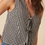 Black and white checkered sleeveless top worn by a person on a beige background