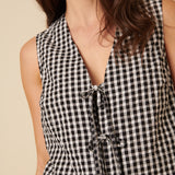 Black and white checkered sleeveless top with a deep neckline on a beige background
