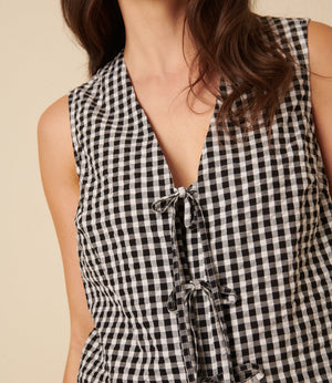 Black and white checkered sleeveless top with a deep neckline on a beige background