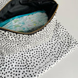 Nappy wallet in dalmatian print, open at an angle showing nappies and wipes inside, with the mat beneath