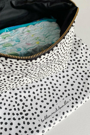 Nappy wallet in dalmatian print, open at an angle showing nappies and wipes inside, with the mat beneath