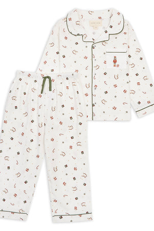 A two-piece children's pajama set featuring a long-sleeve button-front top and matching pants. The pajamas are off-white with a small all-over print of red, brown, and dark green candy and gift motifs, accented with dark green piping and a green drawstring.