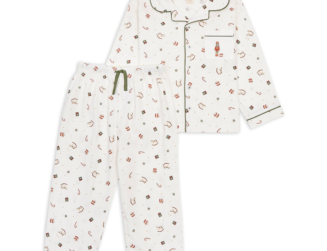 A two-piece children's pajama set featuring a long-sleeve button-front top and matching pants. The pajamas are off-white with a small all-over print of red, brown, and dark green candy and gift motifs, accented with dark green piping and a green drawstring.