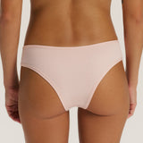 Rear view of a model wearing a light pink seamless high-waisted bikini bottom against a light beige studio background.