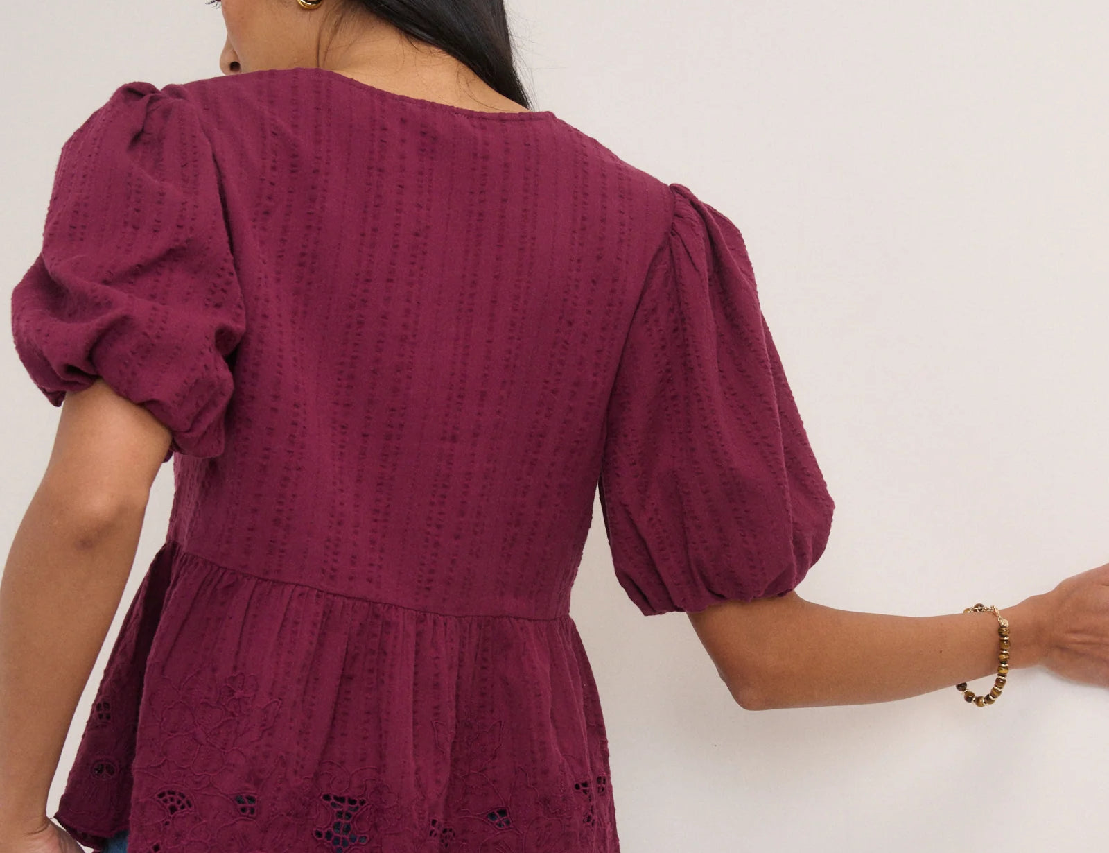 Woman wearing a burgundy top with puff sleeves against a white background