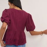 Woman wearing a burgundy top with puff sleeves against a white background