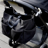 Black stroller with attached black bag on a wooden floor
