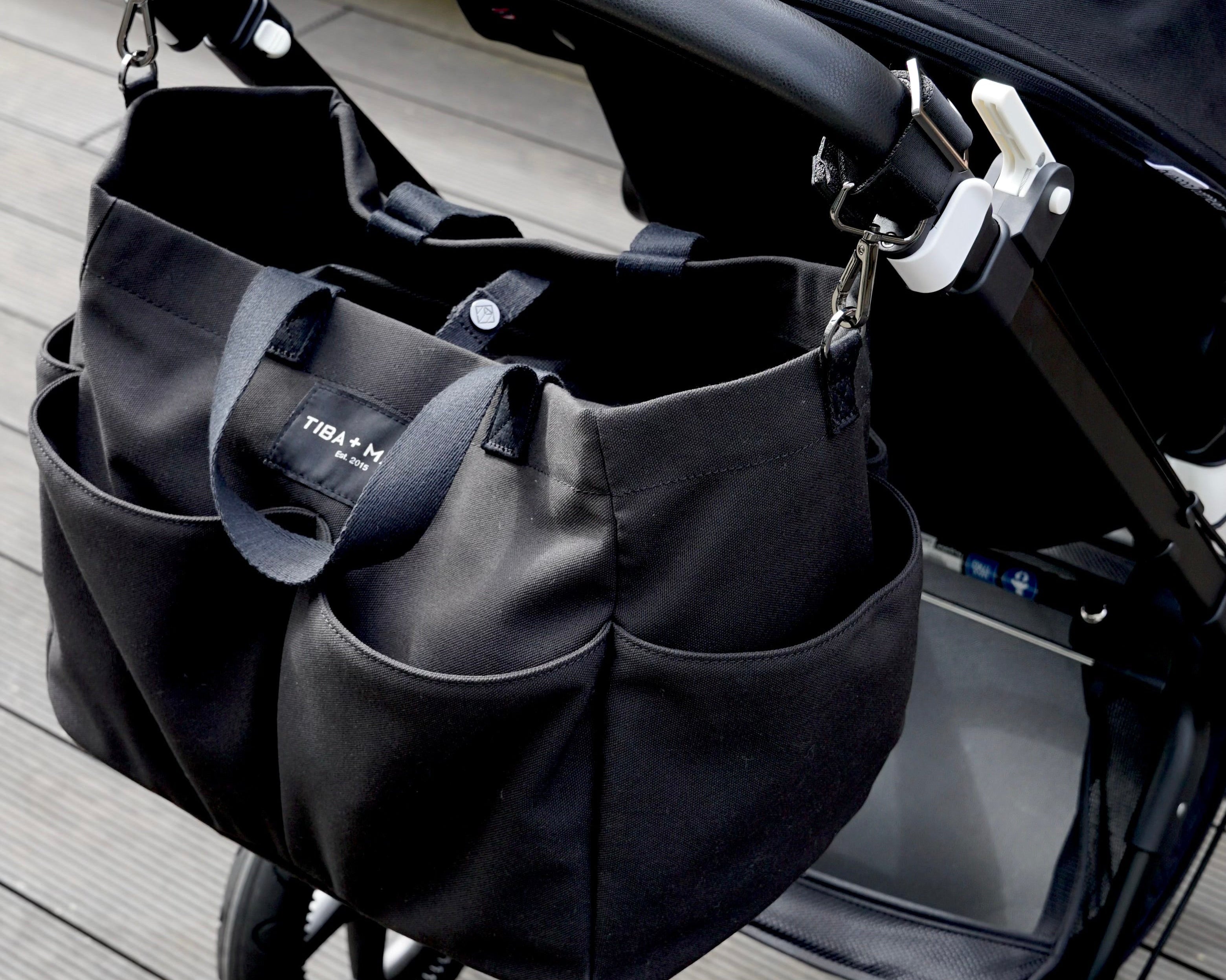 Black stroller with attached black bag on a wooden floor