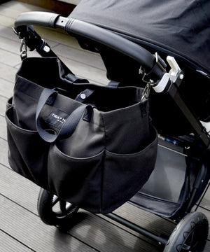 Black stroller with attached black bag on a wooden floor