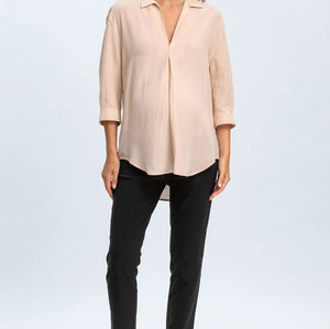 Woman wearing a beige blouse and black pants on a white background