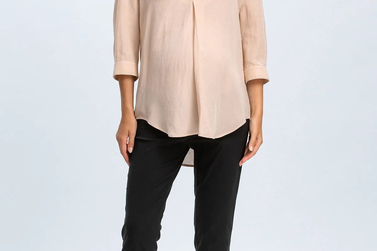 Woman wearing a beige blouse and black pants on a white background