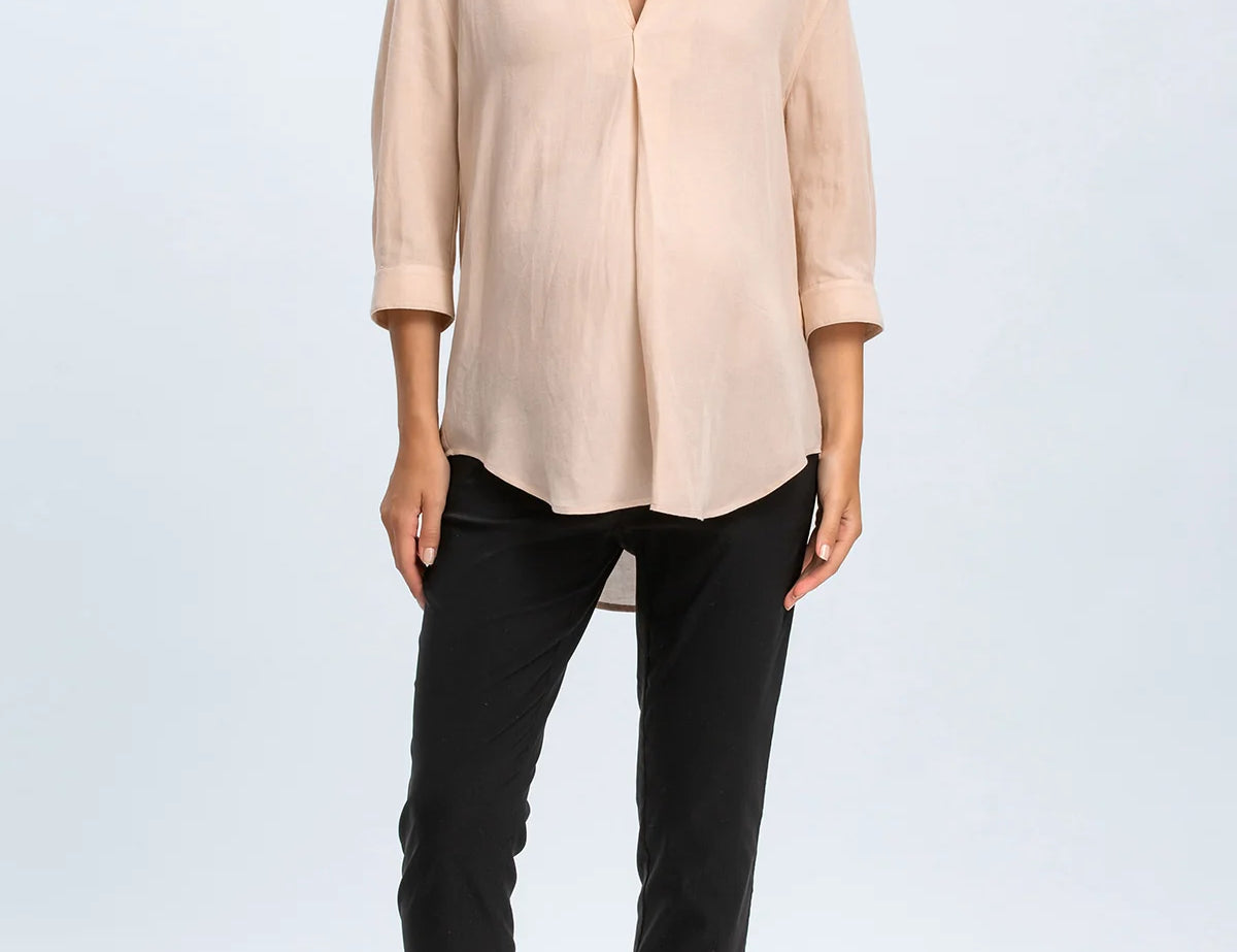 Woman wearing a beige blouse and black pants on a white background