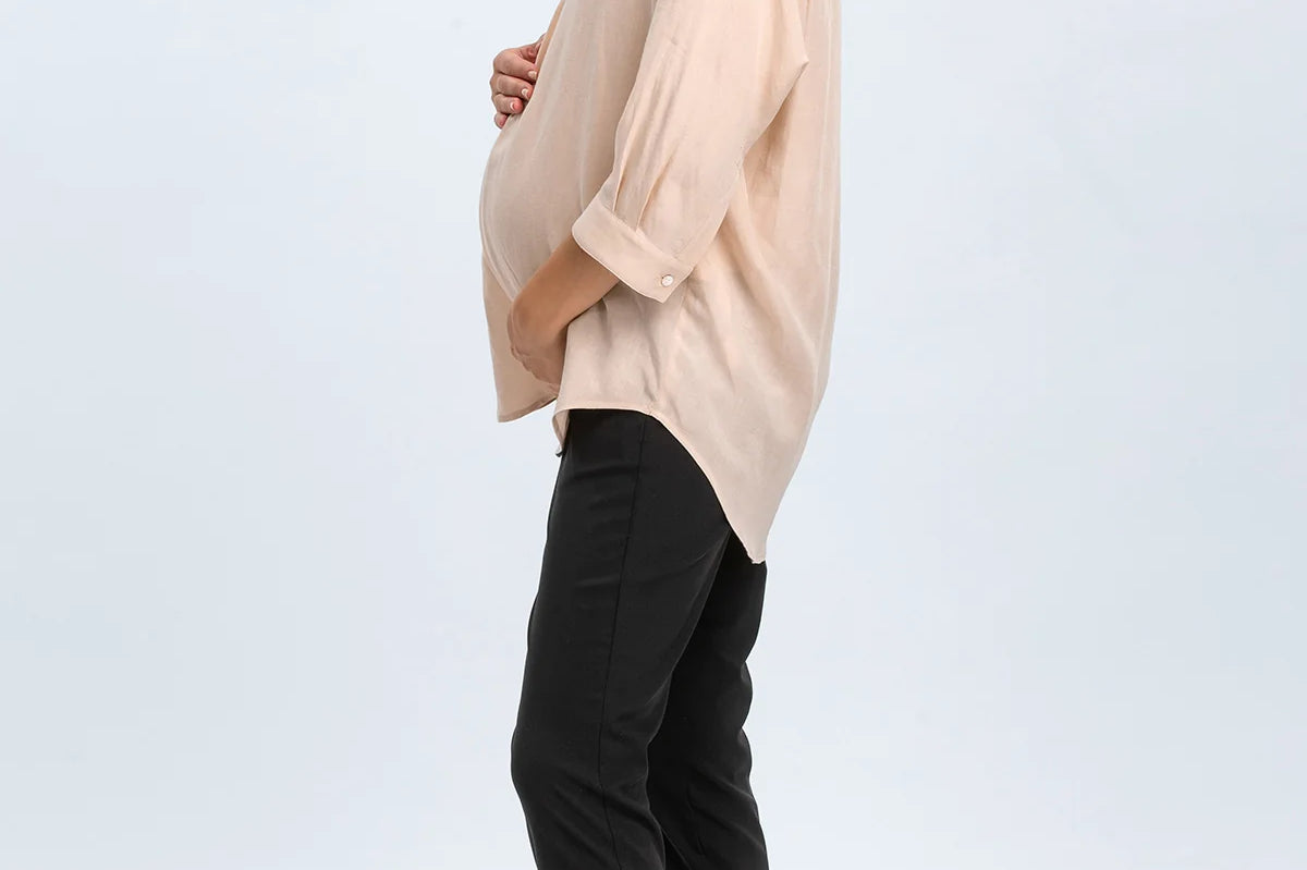 Woman wearing a beige blouse and black pants on a white background