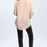 Woman wearing a beige shirt and black pants on a white background