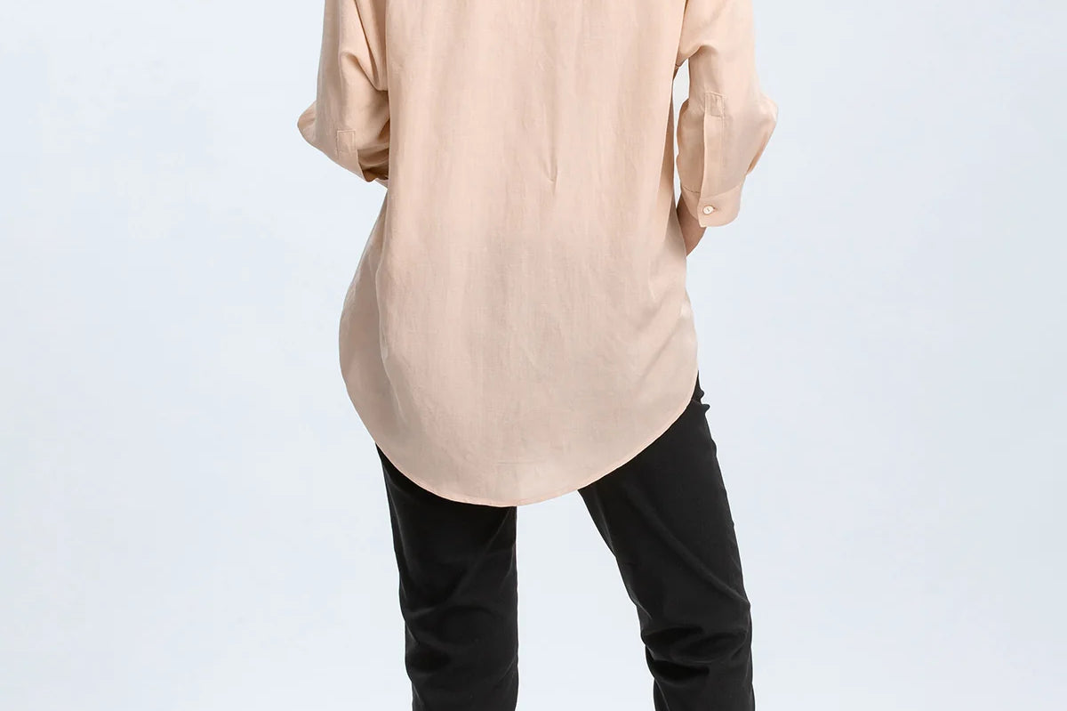 Woman wearing a beige shirt and black pants on a white background