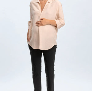 Woman wearing a beige blouse and black pants on a white background