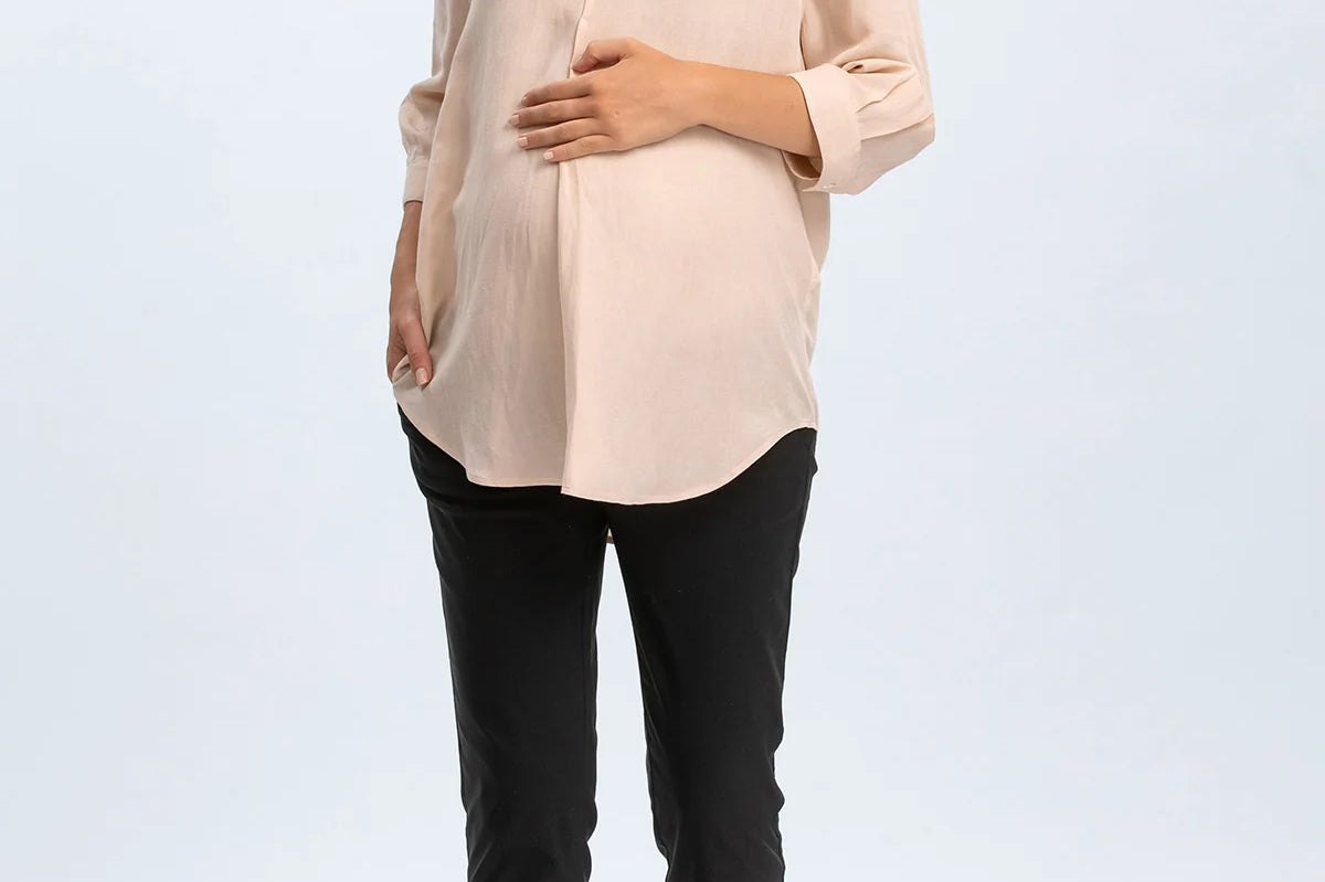 Woman wearing a beige blouse and black pants on a white background