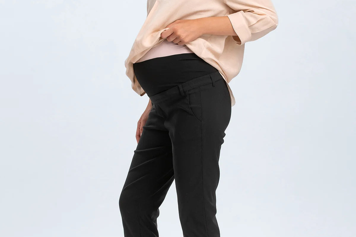 Woman wearing a beige blouse and black pants on a white background