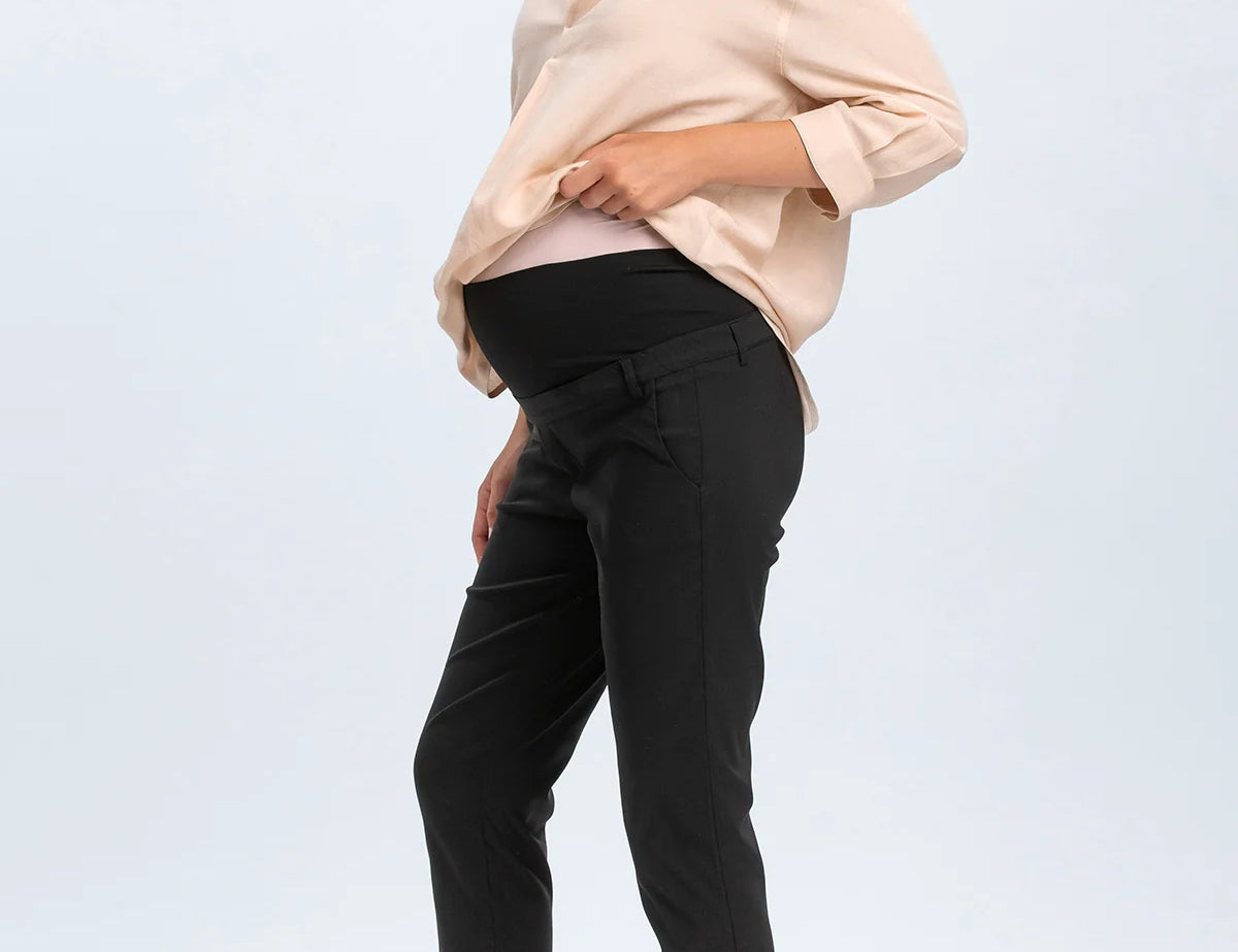 Woman wearing a beige blouse and black pants on a white background