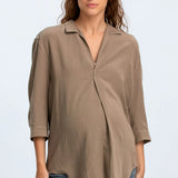 Woman wearing a brown blouse and blue jeans on a light gray background