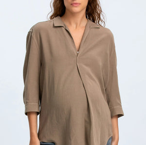 Woman wearing a brown blouse and blue jeans on a light gray background