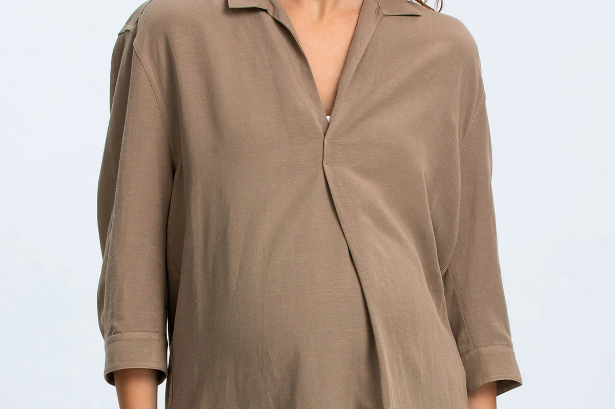 Woman wearing a brown blouse and blue jeans on a light gray background