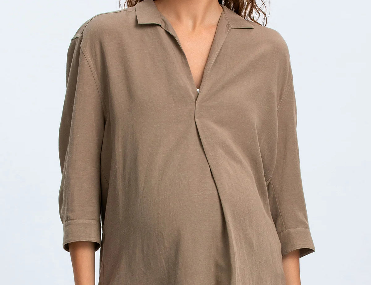 Woman wearing a brown blouse and blue jeans on a light gray background