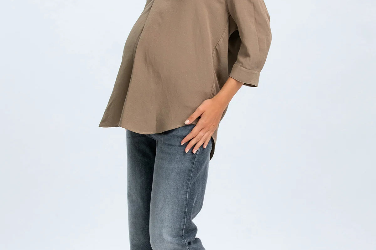 Woman wearing a brown blouse and blue jeans on a white background
