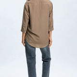 Woman wearing a brown shirt and blue jeans on a white background