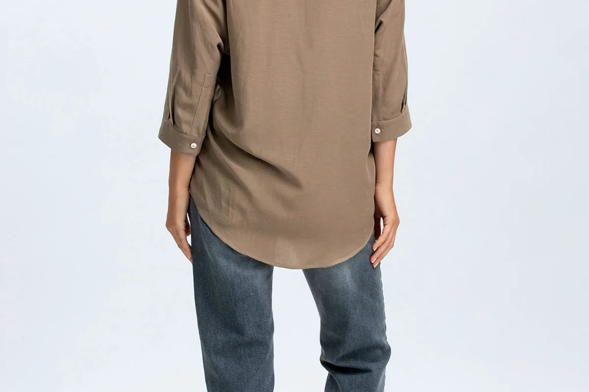 Woman wearing a brown shirt and blue jeans on a white background