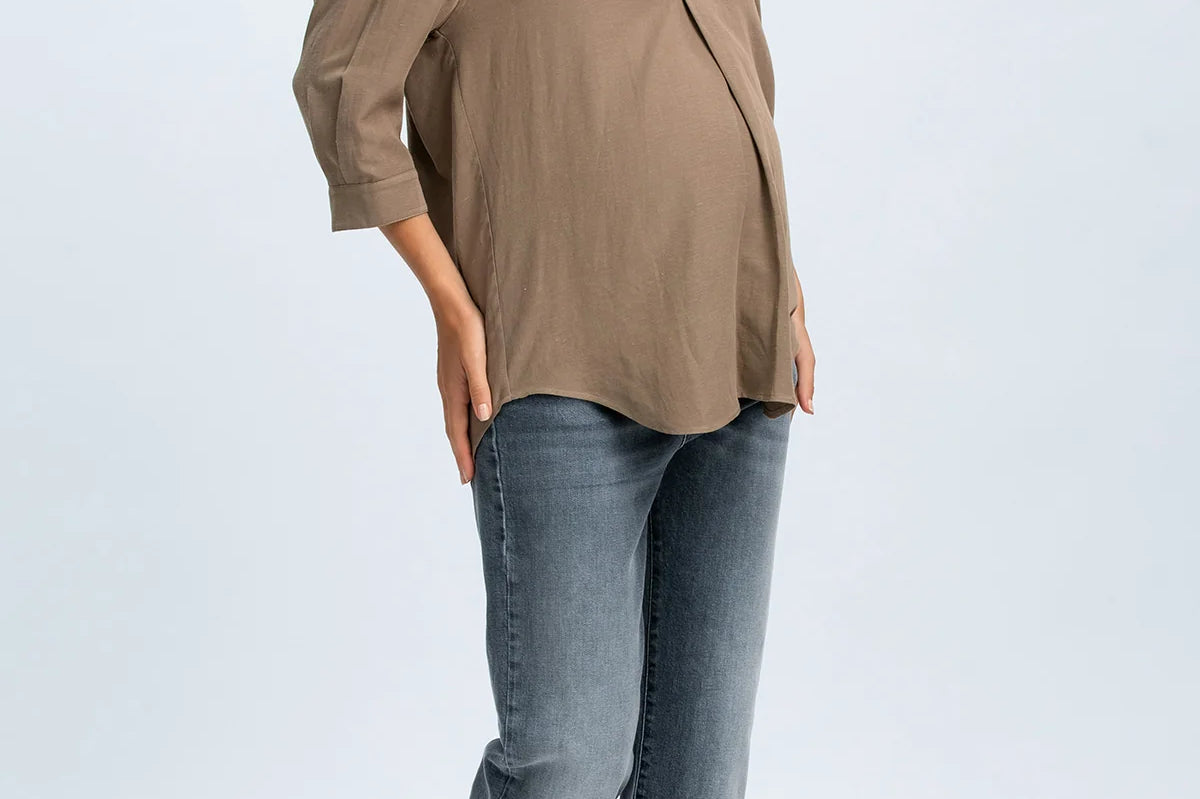 Woman wearing a beige blouse and blue jeans on a white background